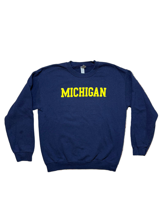 Navy blue sweatshirt with 'MICHIGAN' in yellow on a textured surface